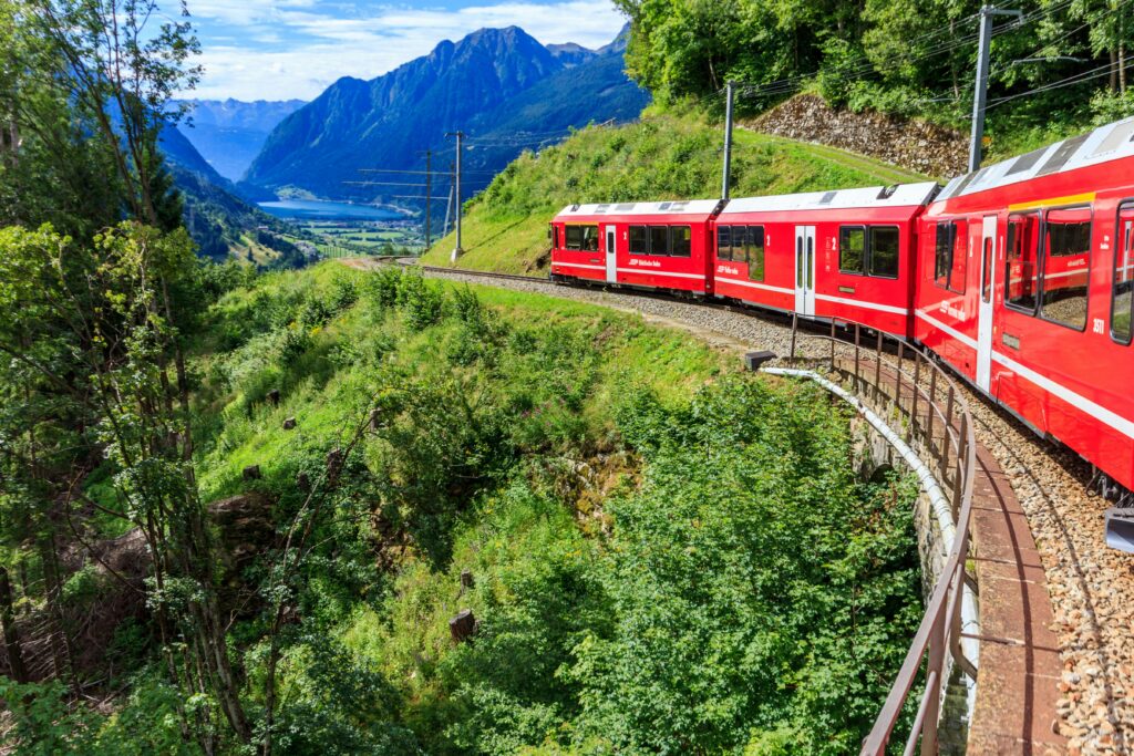 Bernina Express train curves through the stunning Swiss Alps, offering breathtaking views of mountains and valleys.