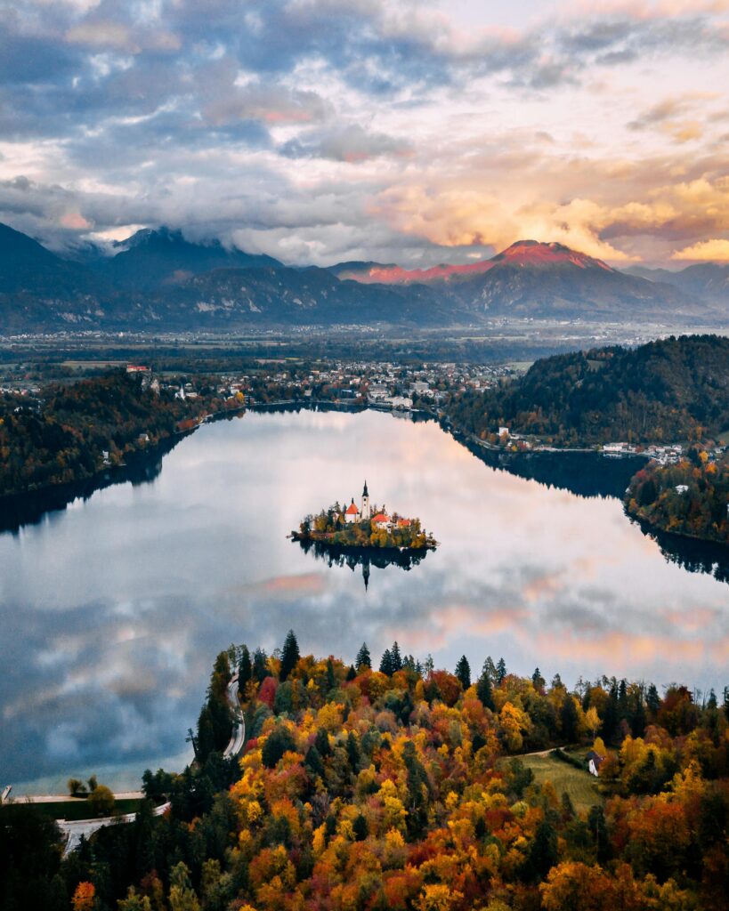 A breathtaking aerial view of Slovenia's Lake Bled surrounded by autumn foliage and mountains.