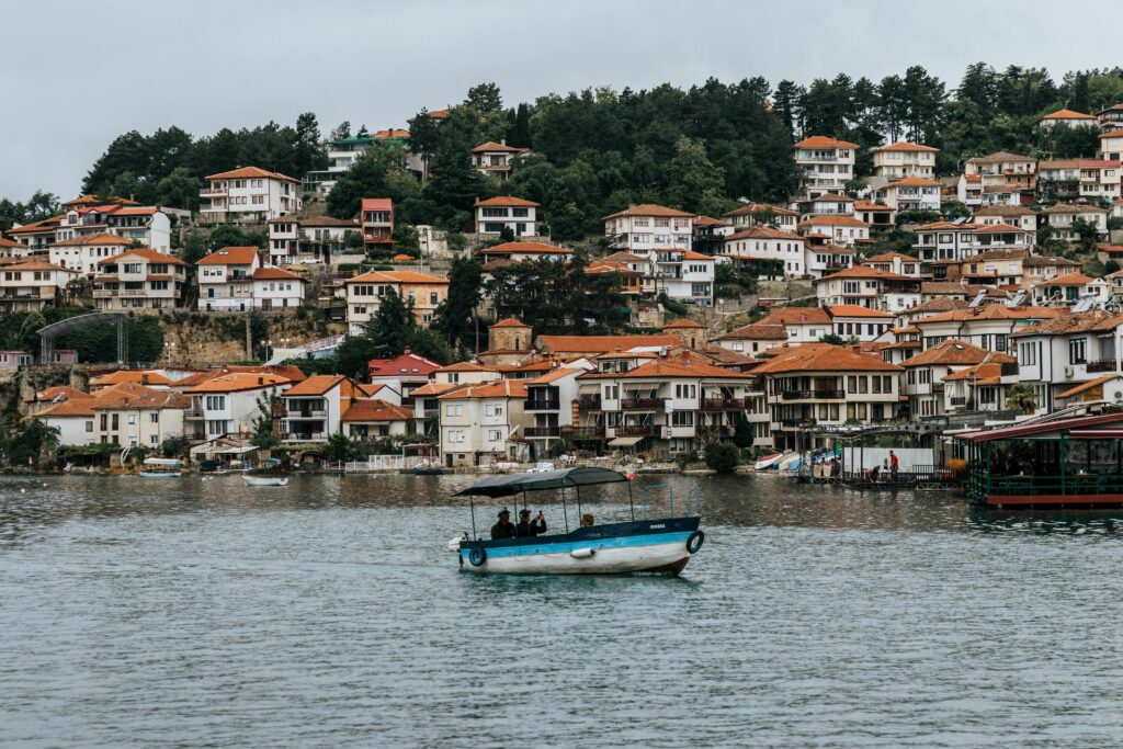 Picturesque view of a waterfront town with traditional houses and a fishing boat gliding across the water.
