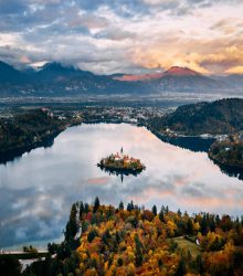 A breathtaking aerial view of Slovenia's Lake Bled surrounded by autumn foliage and mountains.