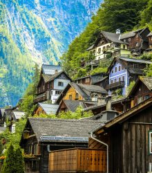 Charming wooden houses on a lush mountainside in Hallstatt, Austria under bright daylight.