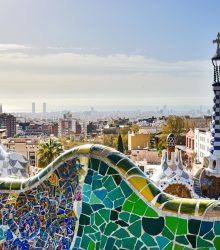 View of Barcelona from Park Güell showcasing mosaic architecture and city skyline.